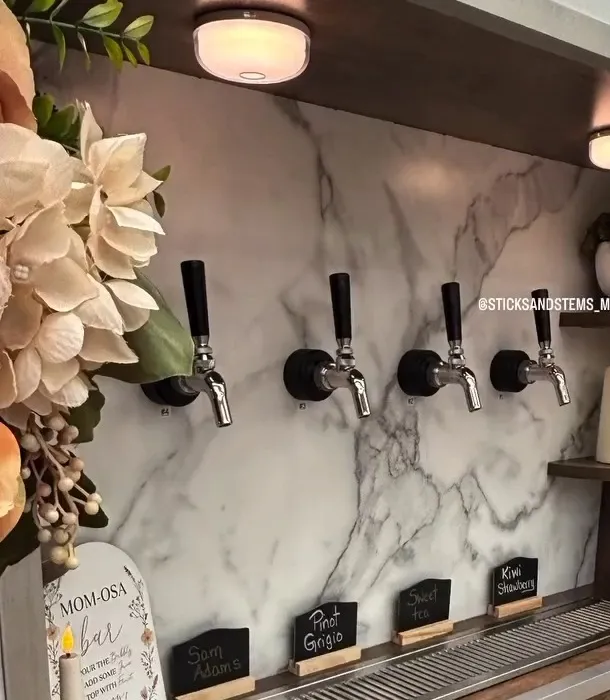 Close-up of the four stainless keg taps on the trailer, with chalkboard drink labels and florals